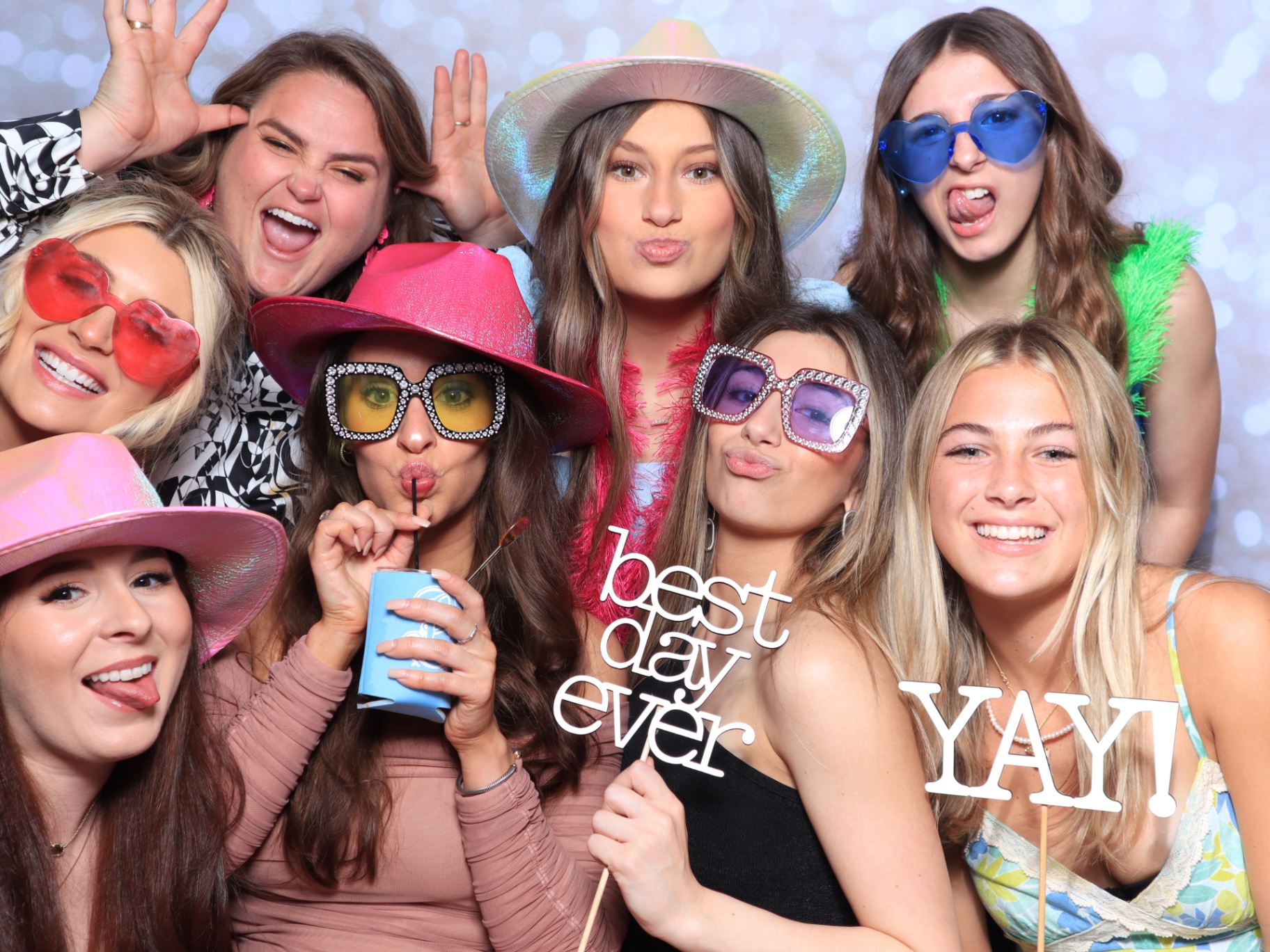 Bride and friends laughing in photo booth props at a wedding